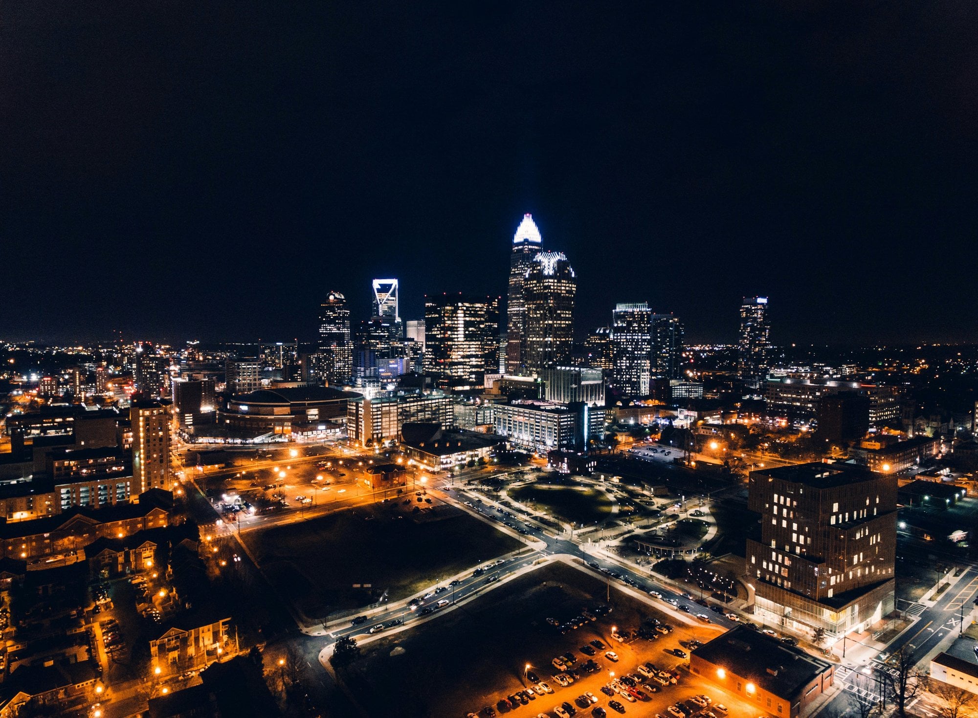 Aerial view of Charlotte, NC skyline at night — glowing city lights and the iconic Duke Energy skyscraper