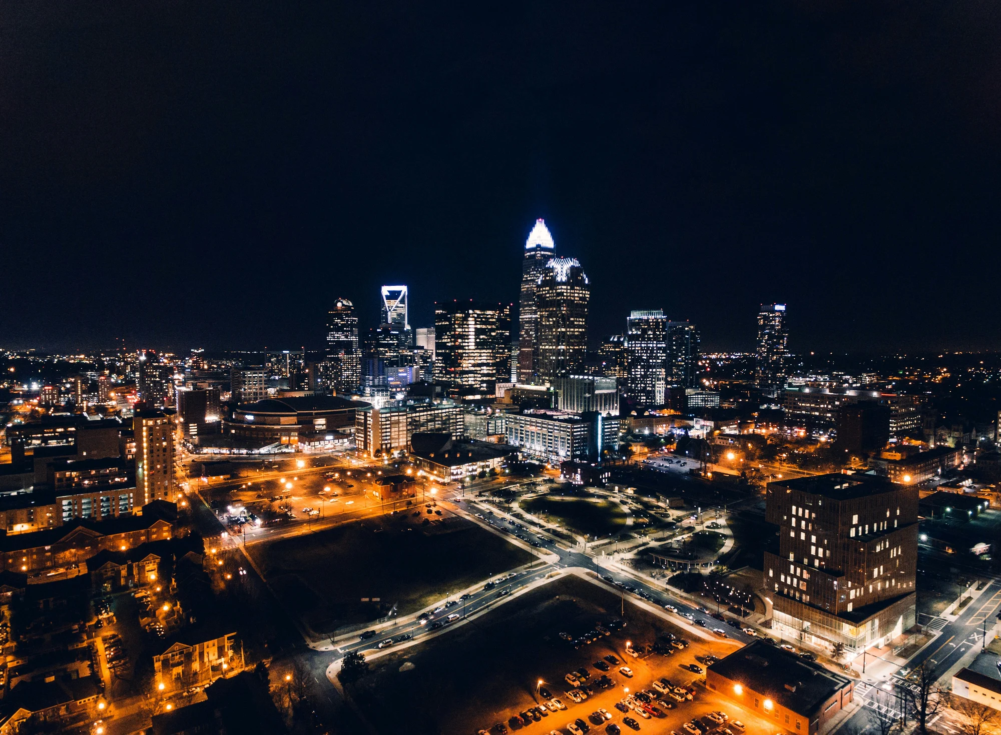 Aerial view of Charlotte, NC skyline at night — glowing city lights and the iconic Duke Energy skyscraper
